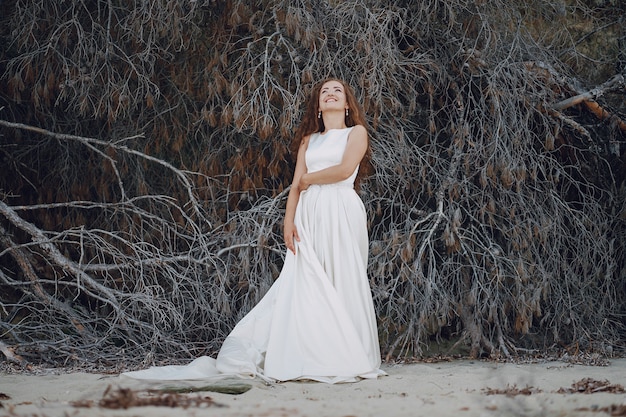 Hermosa novia de pelo largo en un magnífico vestido blanco en la naturaleza