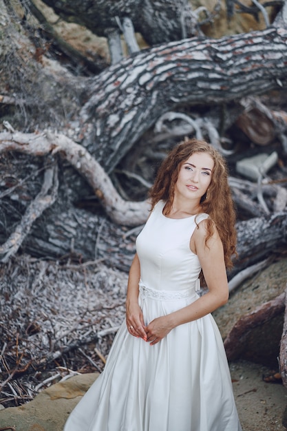 Hermosa novia de pelo largo en un magnífico vestido blanco en la naturaleza