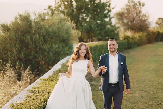 hermosa novia de pelo largo en vestido blanco con su joven caminando en la naturaleza