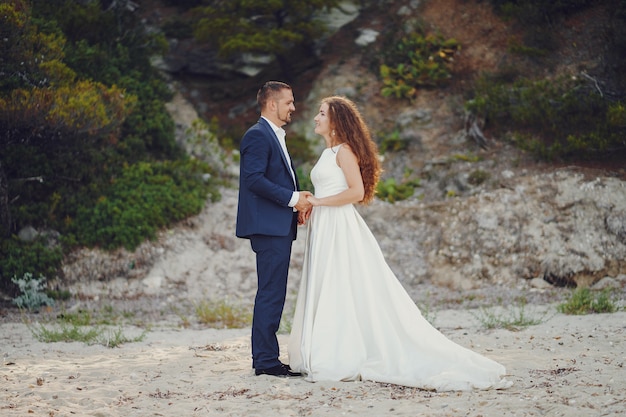 hermosa novia de pelo largo en vestido blanco con su joven caminando en la naturaleza