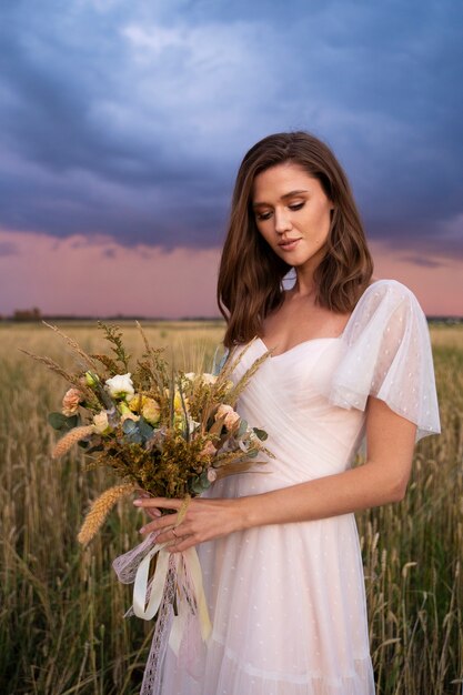 Hermosa novia sosteniendo flores vista lateral