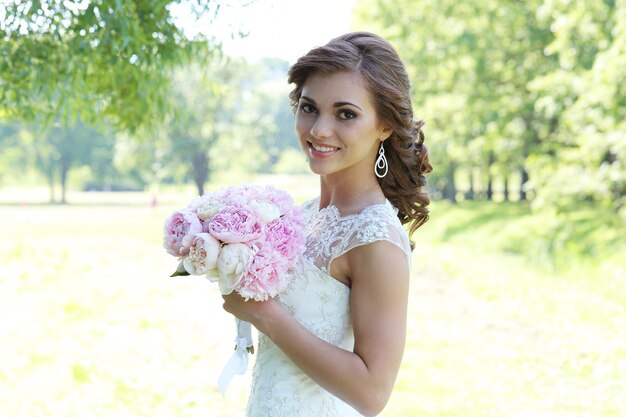 Hermosa novia en updo rizado en la naturaleza de tha