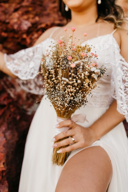 Hermosa novia con un vestido blanco y sosteniendo un ramo de flores