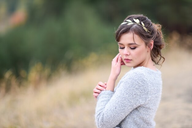 Hermosa novia en vestido rosa y chaqueta azul se encuentra en el viento en algún lugar de un bosque