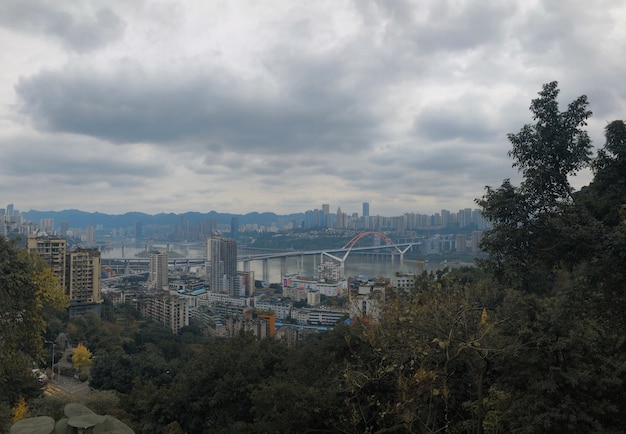 Hermosa panorámica de Yuzhong Qu, China con cielo nublado y vegetación en primer plano