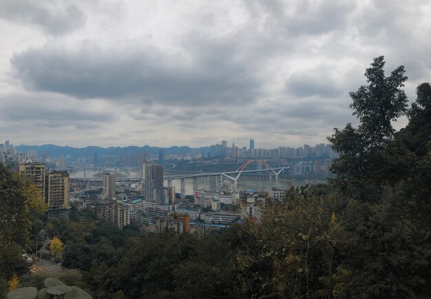 Hermosa panorámica de Yuzhong Qu, China con cielo nublado y vegetación en primer plano