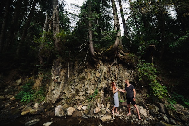 Hermosa pareja abrazándose cerca de un río de montaña