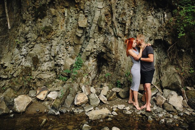 Hermosa pareja abrazándose cerca de un río de montaña