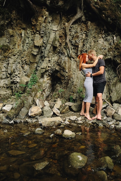 Hermosa pareja abrazándose cerca de un río de montaña
