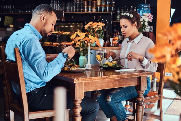 Hermosa pareja afroamericana enamorada pasando un buen rato juntos en su cita, una pareja atractiva disfrutando el uno del otro, comiendo en un restaurante.