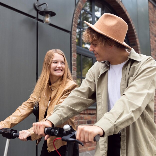 Hermosa pareja al aire libre en la ciudad con scooters eléctricos