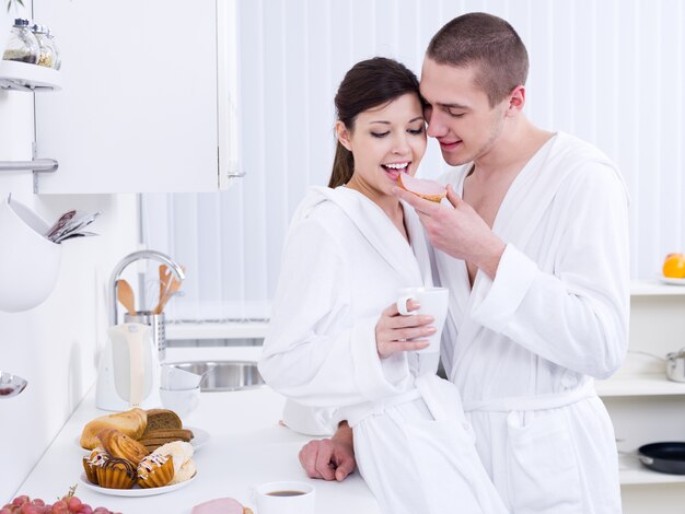 Hermosa pareja amorosa feliz desayunando en la cocina