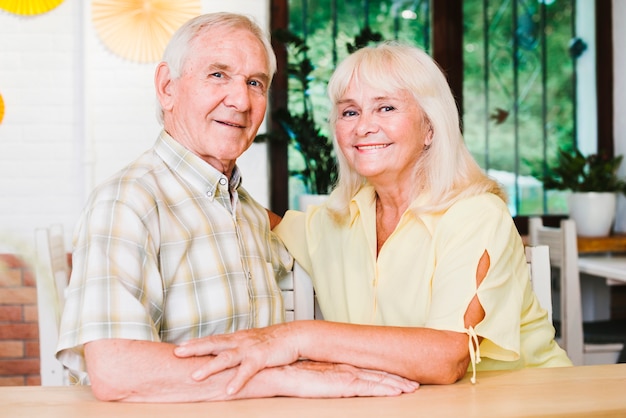 Hermosa pareja de ancianos acurrucarse y mirando a cámara