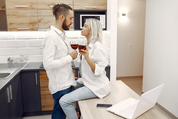 Hermosa pareja bebe vino tinto en la cocina