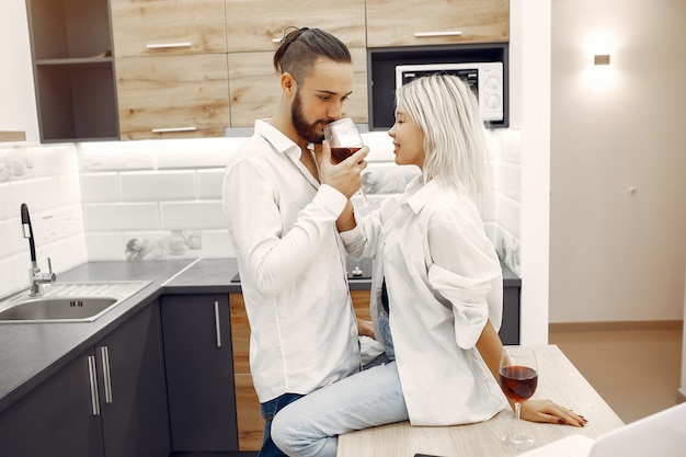Hermosa pareja bebe vino tinto en la cocina