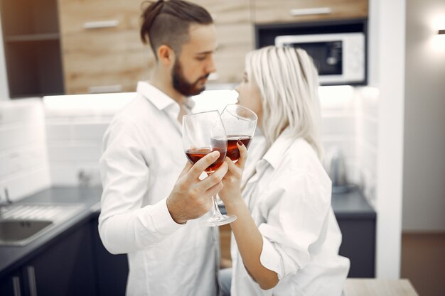 Hermosa pareja bebe vino tinto en la cocina