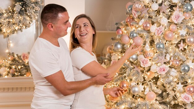 Hermosa pareja decorando el árbol de navidad