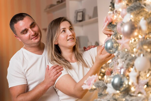 Hermosa pareja decorando el árbol de navidad