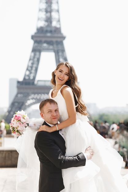 Hermosa pareja se divierte posando en la plaza antes de la Torre Eiffel en París