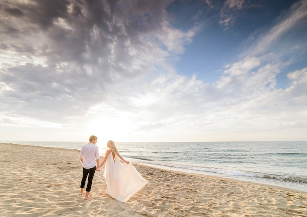 Hermosa pareja elegante caminando en la playa