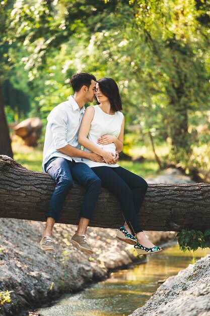 Hermosa pareja embarazada relajante afuera en el bosque