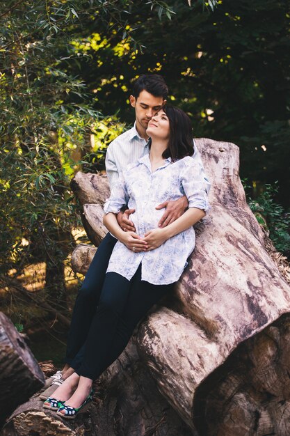 Hermosa pareja embarazada relajante afuera en el bosque