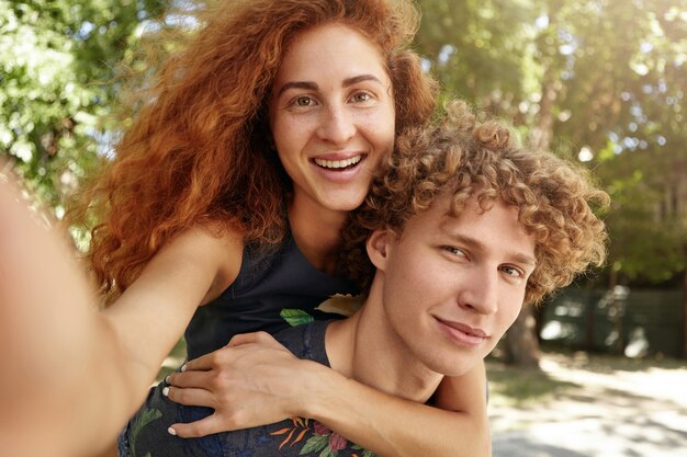 Hermosa pareja de enamorados divirtiéndose en el parque verde tomando selfie