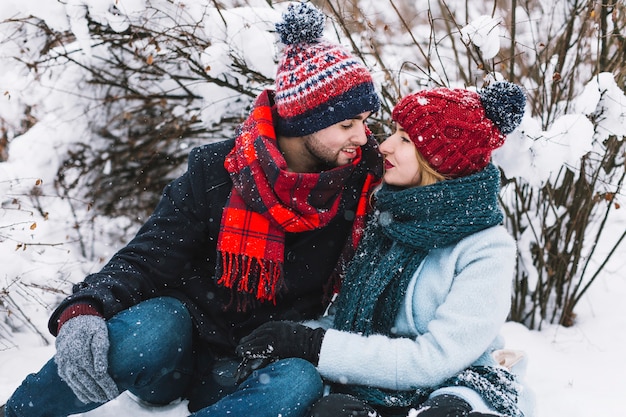 Hermosa pareja de enamorados sentados en la nieve