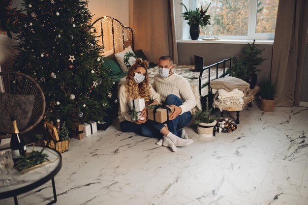 Hermosa pareja de enamorados se sienta en el suelo cerca del árbol de Navidad