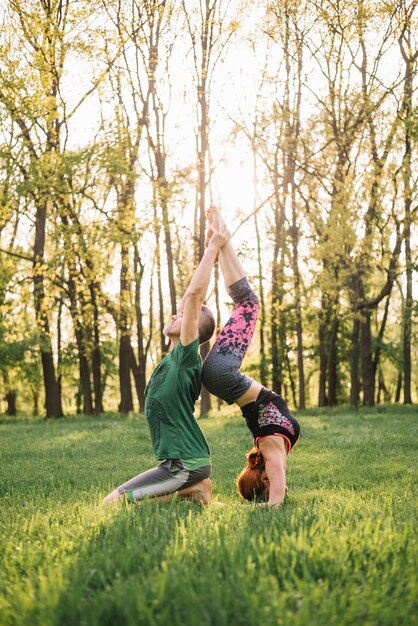 Hermosa pareja haciendo acro yoga en pasto