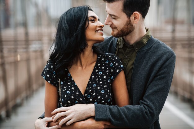 Hermosa pareja de hombre americano con barba y tierna mujer oriental se abrazan