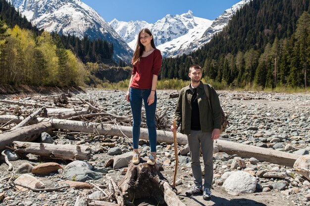 Hermosa pareja joven inconformista senderismo en el río en el bosque