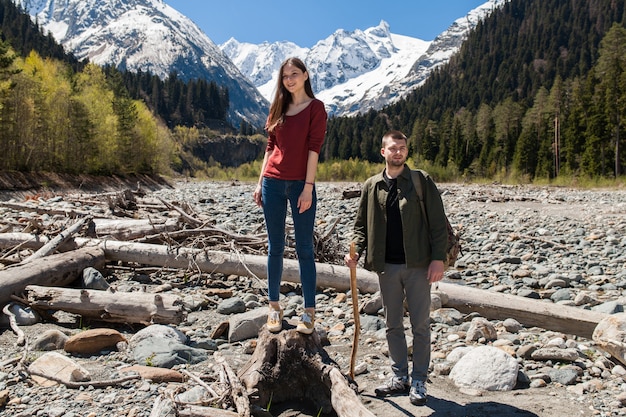 Hermosa pareja joven inconformista senderismo en el río en el bosque