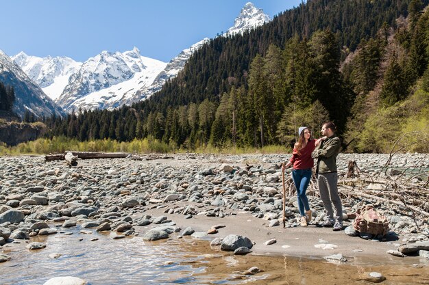 Hermosa pareja joven inconformista senderismo en el río en el bosque