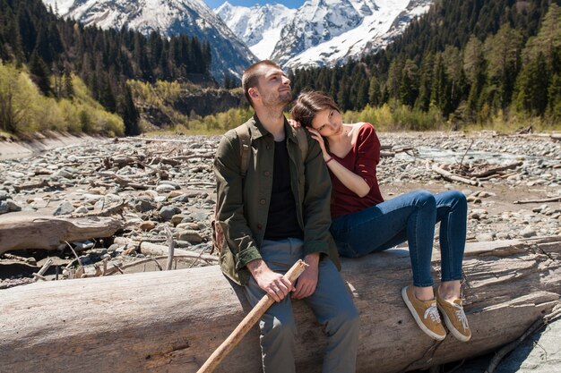 Hermosa pareja joven inconformista senderismo en el río en el bosque