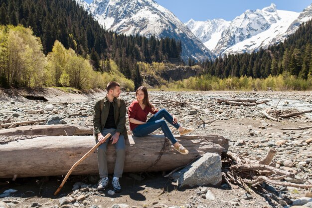 Hermosa pareja joven inconformista senderismo en el río en el bosque