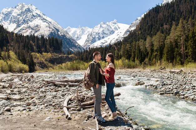 Hermosa pareja joven inconformista senderismo en el río en el bosque