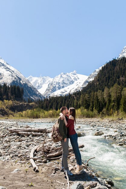 Hermosa pareja joven inconformista senderismo en el río en el bosque