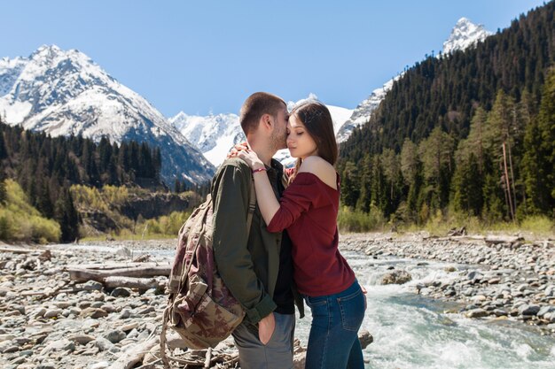 Hermosa pareja joven inconformista senderismo en el río en el bosque