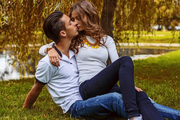 Hermosa pareja joven relajándose en el campo de hierba en un parque.