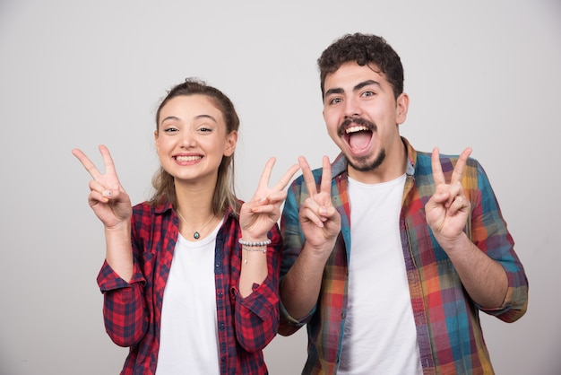 Hermosa pareja juntos vistiendo camisa a cuadros sobre sonriendo con cara feliz haciendo el signo de la victoria.