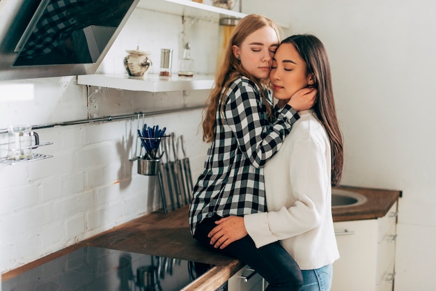 Hermosa pareja de lesbianas abrazando en la cocina