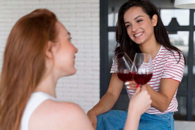 Hermosa pareja de lesbianas animando con unas copas de vino