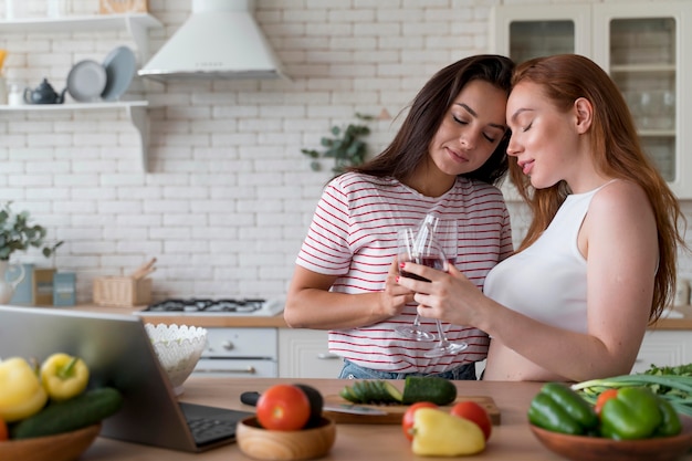 Hermosa pareja de lesbianas animando con unas copas de vino