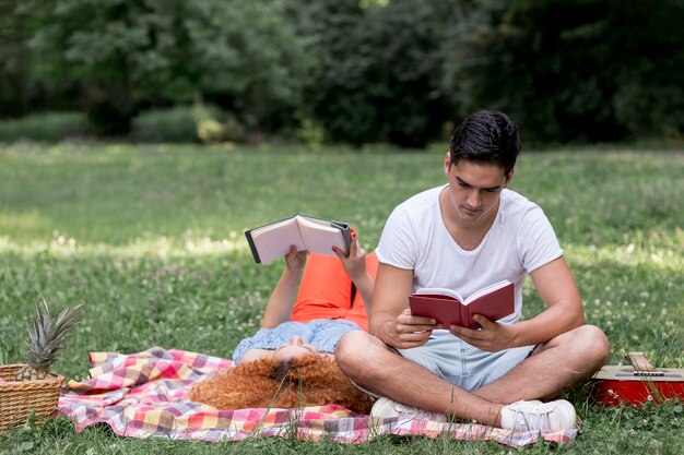 Hermosa pareja leyendo libros y haciendo picnic