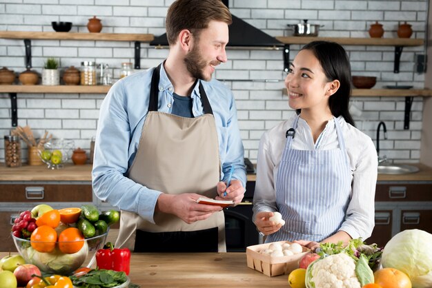 Hermosa pareja mirando el uno al otro mientras el hombre escribiendo la receta en el diario