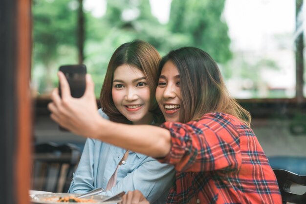 Hermosa pareja de mujeres asiáticas lesbianas lgbt sentadas a cada lado comiendo un plato de mariscos italianos