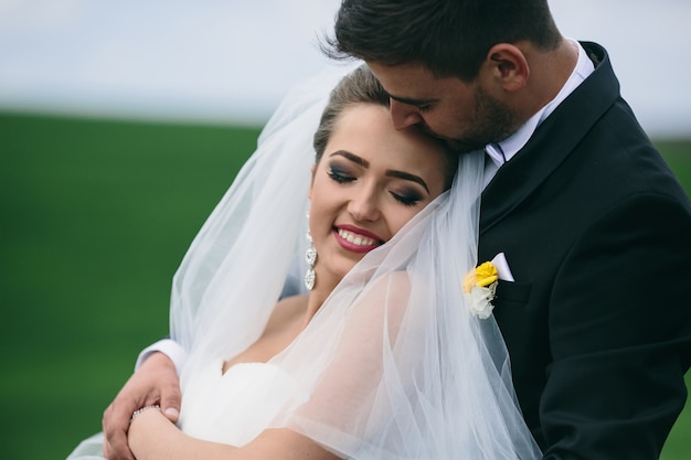 Hermosa pareja de novios está caminando en el campo verde