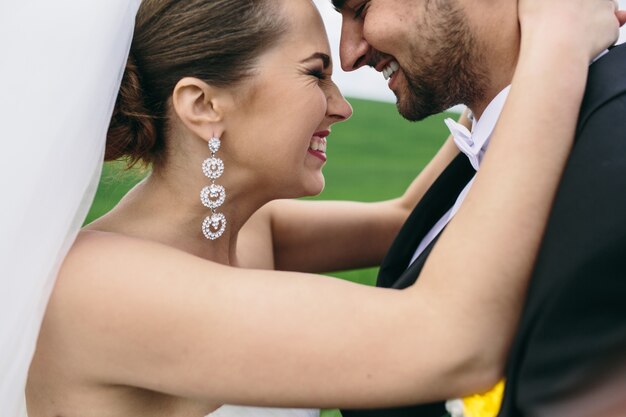 Hermosa pareja de novios está caminando en el campo verde