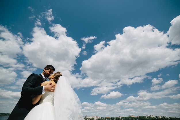 Hermosa pareja de novios en el fondo de cielo azul, agua